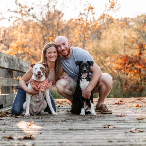 couple with dogs on bridge in woods pet photography